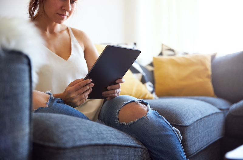 woman looking at a tablet while sitting on a couch