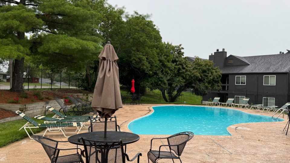 a pool with chairs and umbrellas near a patio at The Windchase Flats and Townhomes